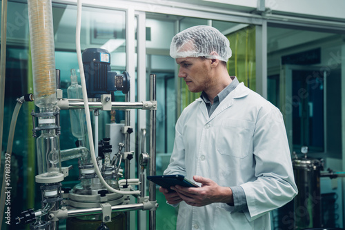 Scientist holding paper board and checking rotational vaporizer during CBD oil extraction, hemp oil extraction process.