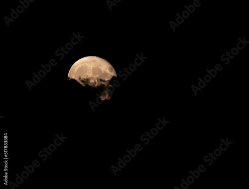 The full moon appearing from behind clouds photo