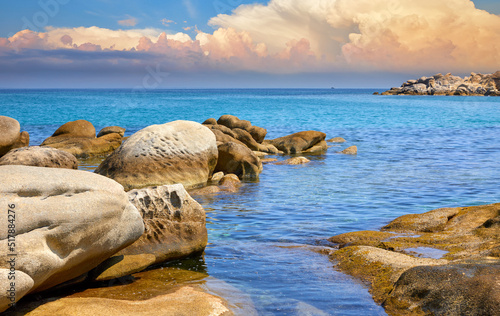 Karidi beach at peninsula Sithonia, Chalkidiki, Greece. Big stones coastline of Aegean sea with blue water. Sea view. Summer sunny day sunset sky clouds. © Yasonya