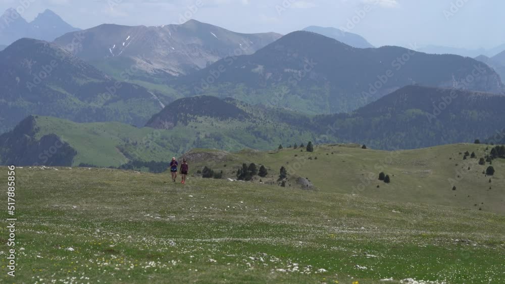 Scenery Of Mountainous Landscape With Hikers Walking Through Spring Fields. Panning Left Shot