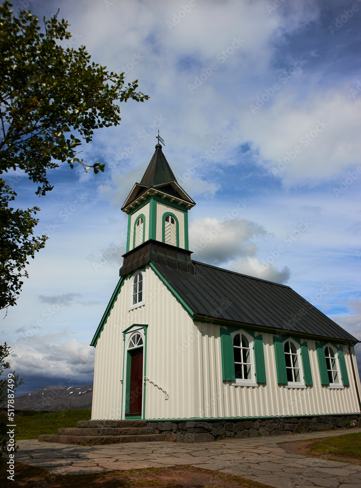 THINGVALLAKIRKJA, first church built in Iceland, beautiful wooden chapel house in a forest with blue sky THINGVALLAKIRKJA, first church built in Iceland, beautiful wooden chapel house in a forest with blue sky