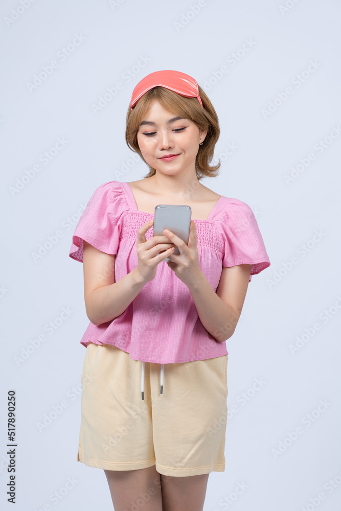 Young beautiful woman wearing pajama and sleep mask having conversation using smartphone Young beautiful woman wearing pajama and sleep mask having conversation using smartphone
