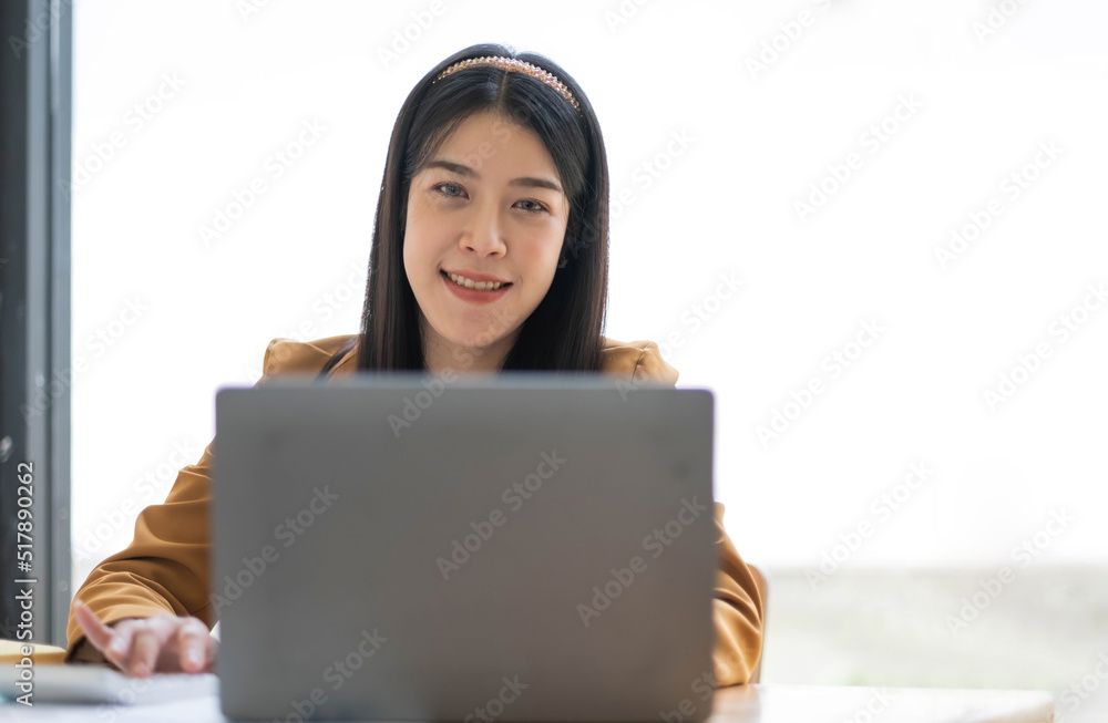 Charming Asian woman working at the office using a laptop Looking at the camera. Charming Asian woman working at the office using a laptop Looking at the camera.