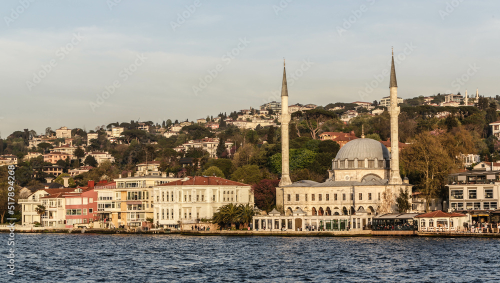 Istanbul, Turkey - April 2022: Locals fish in the waters of the Bosphorus outside Beylerbeyi Mosque, also known as Hamid-i Evvel Camii, in Beylerbeyi in the Uskudar district of Istanbul