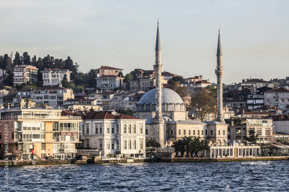 Istanbul, Turkey - April 2022: Locals fish in the waters of the Bosphorus outside Beylerbeyi Mosque, also known as Hamid-i Evvel Camii, in Beylerbeyi in the Uskudar district of Istanbul