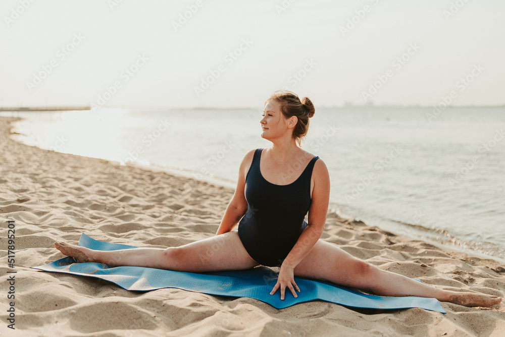 Caucasian woman practicing yoga at seashore sandy beach on sunrise. Womens health and wellness. Sports body positive. Real instructor poses