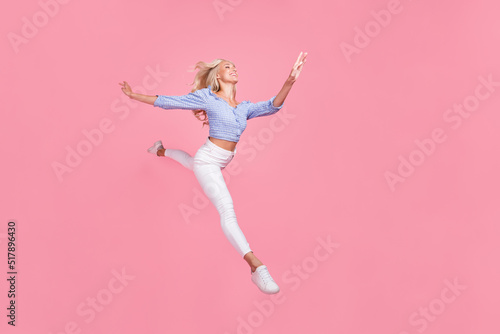 Fototapeta Naklejka Na Ścianę i Meble -  Full length photo of pretty sweet girl dressed blue top jumping high running empty space isolated pink color background
