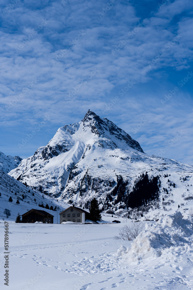 Fototapeta premium a mountain in Galtür covered in snow, in the foreground 2 huts