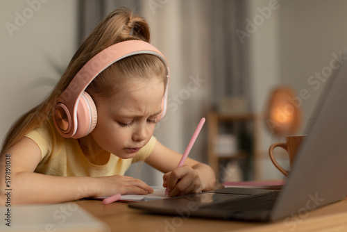 Schoolgirl Taking Notes Doing Homework Online Using Laptop At Home