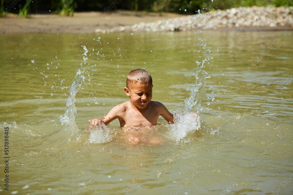 Fototapeta premium A boy is bathing in yellow river water. Rural recreation.