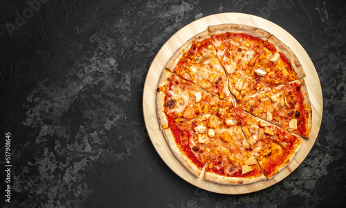 Tasty hawaiian pizza with chicken and pineapple on wooden cutting board on a dark background. food delivery, place for text, top view