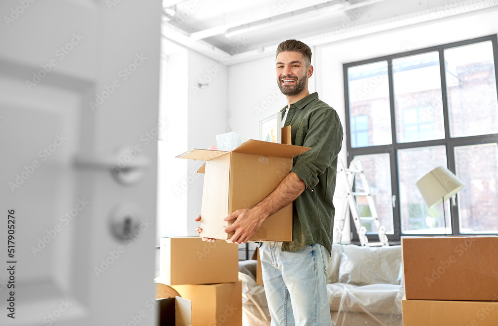 moving, people and real estate concept - happy smiling man holding box with stuff at new home moving, people and real estate concept - happy smiling man holding box with stuff at new home