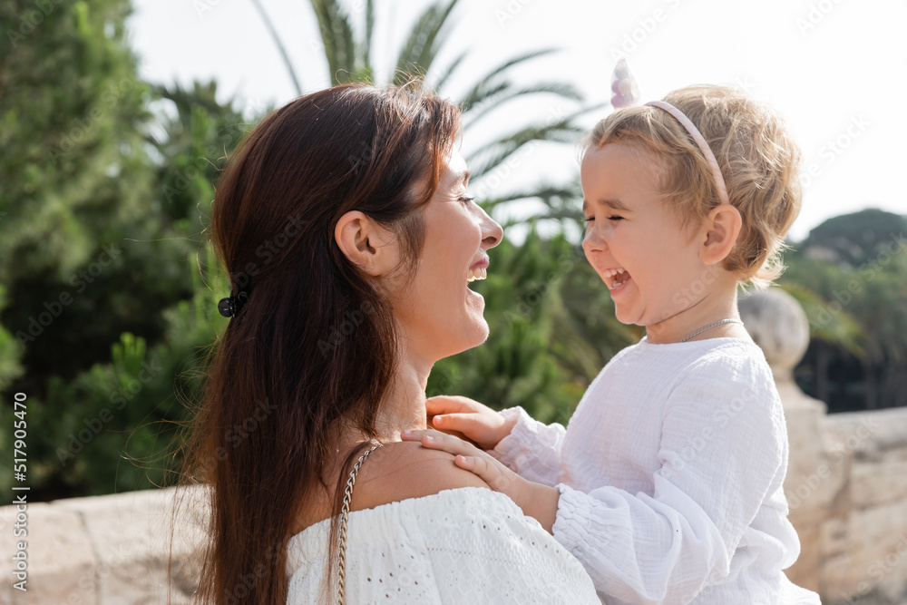 Brunette mother holding baby daughter and laughing in Valencia. Brunette mother holding baby daughter and laughing in Valencia.