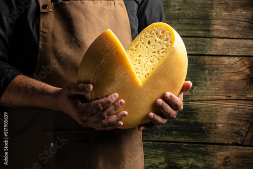 Foto A head of hard cheese in man's cheesemaker hands