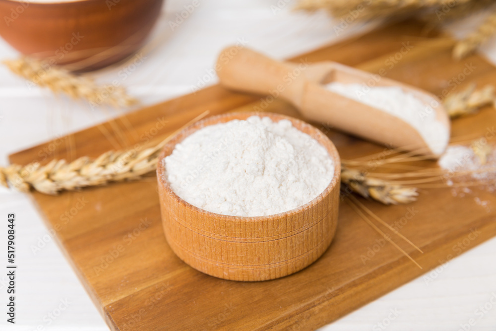 Flat lay of Wheat flour in wooden bowl with wheat spikelets on colored background. world wheat crisis Flat lay of Wheat flour in wooden bowl with wheat spikelets on colored background. world wheat crisis
