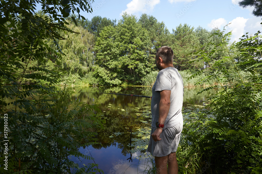 Naklejka premium Caucasian adult man fishing on the river with beautiful view of landscape.