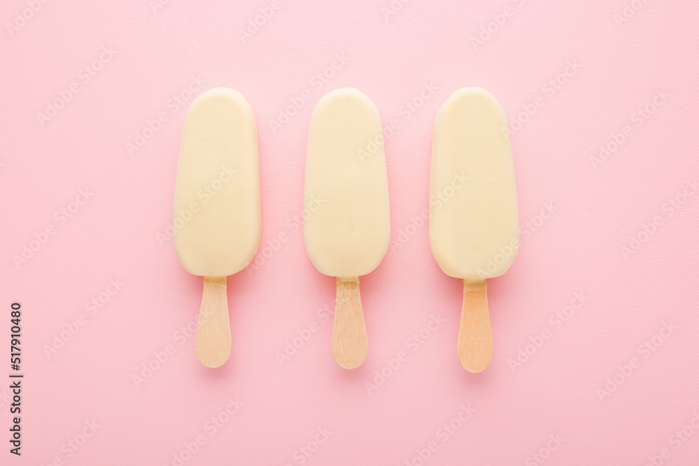 Three chocolate ice cream with white vanilla glaze on sticks. Light pink table background. Pastel color. Closeup. Cold sweet snack in summer. Top down view. Three chocolate ice cream with white vanilla glaze on sticks. Light pink table background. Pastel color. Closeup. Cold sweet snack in summer. Top down view.