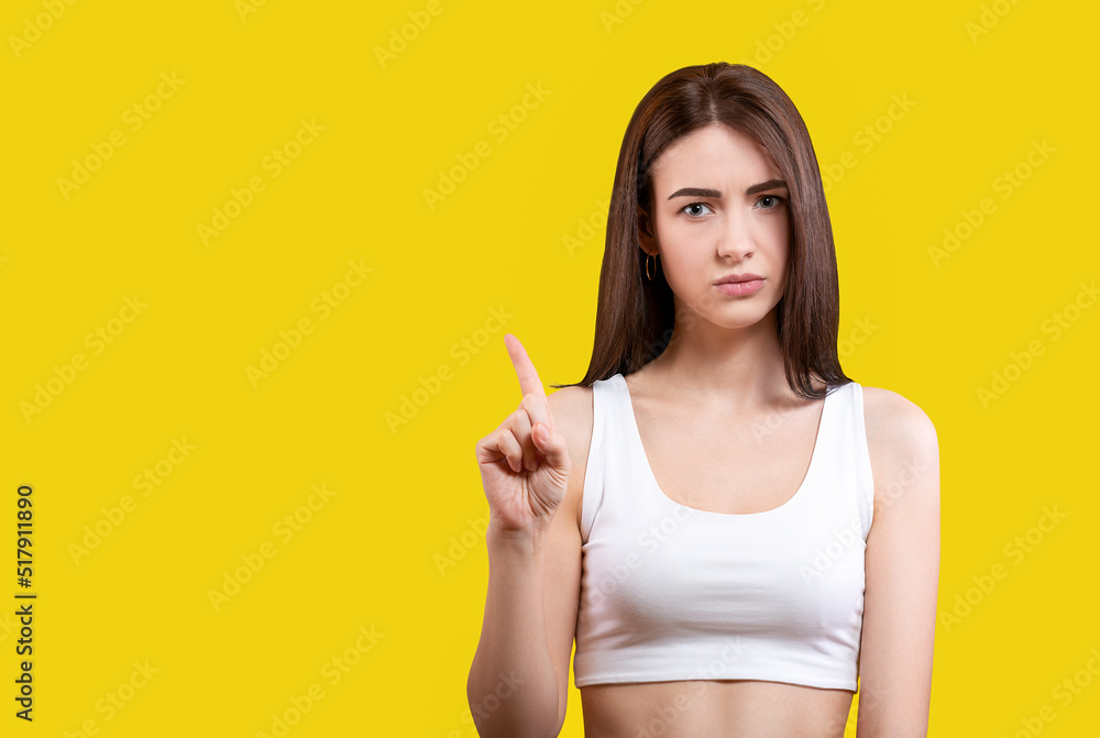 Portrait of an attractive angry girl in a white top on a yellow background. Portrait of an attractive angry girl in a white top on a yellow background.