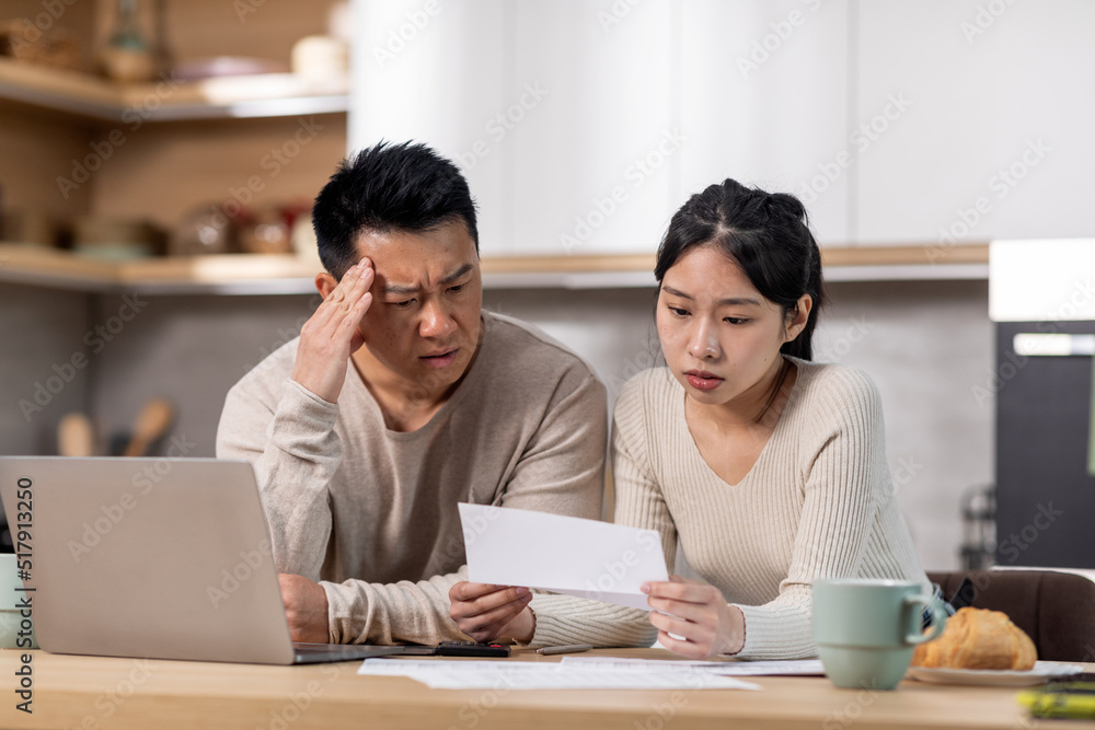 Upset korean husband and wife reading letter, kitchen interior Upset korean husband and wife reading letter, kitchen interior