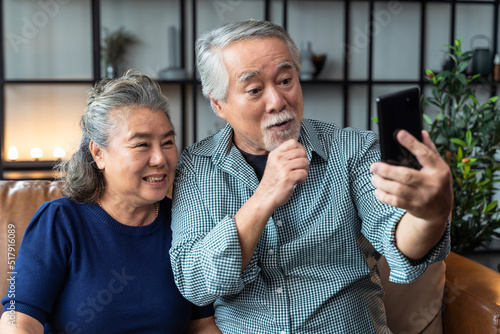 happiness asian old senior retired couple enjoy videocall to family together on sofa in living room at home,asian people use smartphone communication to family home isolation ides concept