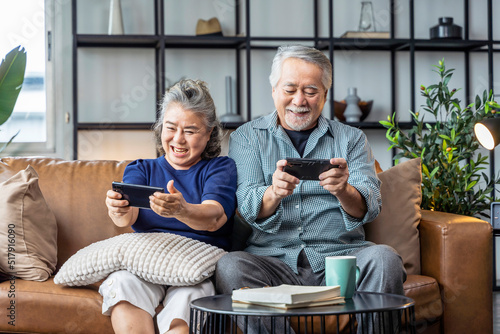 happiness asian retired couple enjoy playing and competition game smartphone mobile online together on sofa living room home interior background asian couple playing game together home isolate ideas