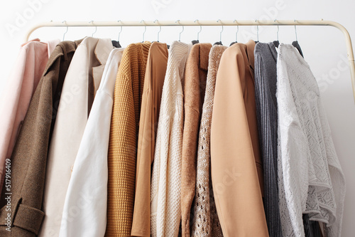 female autumn clothes on hangers in white room