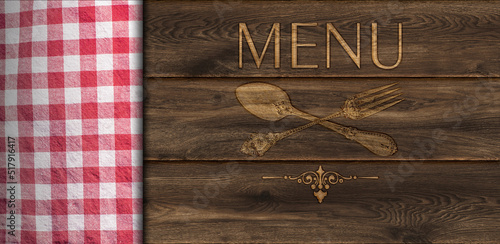 Cloth napkin on rustic wooden board table background, top view. The inscription Menu and the contour of the fork and spoon are burnt on a wooden board.