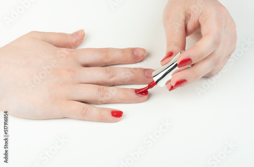 A young woman applies polish to her fingernails.