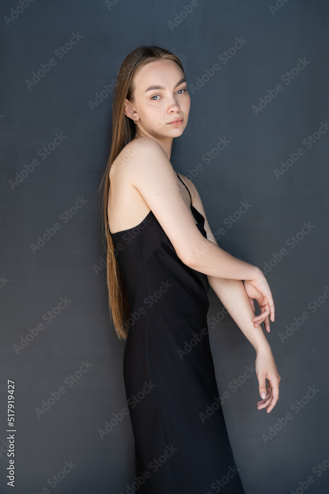 young long haired woman in strap dress looking at camera on black background. young long haired woman in strap dress looking at camera on black background.