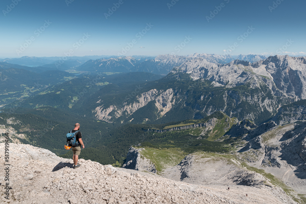 Mountaineer at the summit from the Alpspitze in Germany looks down to the valley and to the Karwendel mountains.