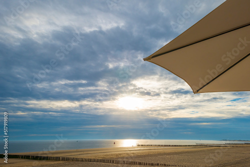 Sand  beach and sand dunes along a sea under a dusk cloudy sky at a bright sunset in summer  Walcheren  Zeeland  the Netherlands  July  2022