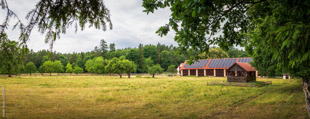 Panorama of the run for horses. Brick barn with photovoltaic panels on a corrugated roof. Beautiful rural landscape. Zwierzyniec, Poland