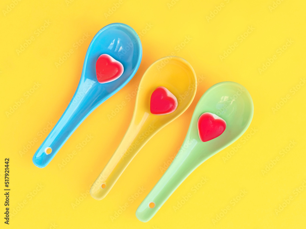 Colourful spoons with Candy Heart Sweets with a vibrant yellow background. Colourful spoons with Candy Heart Sweets with a vibrant yellow background.