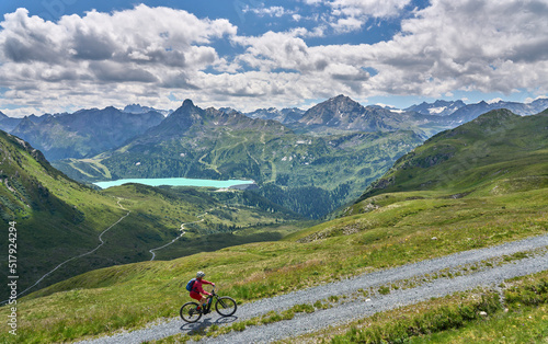 nice active senior woman riding her electric mountain bike in the silvretta mountain range above barrier lake Kopssee,near Gaschurn, Tyrol, Austria