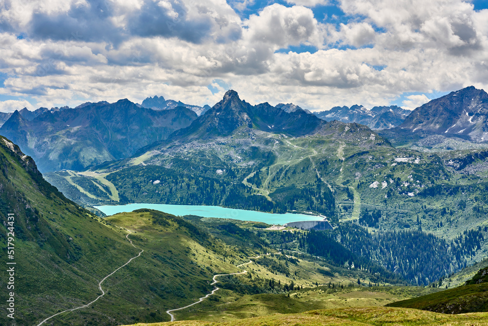 mountain landscape with cloud sky in the silvretta mountain range above cyan colored Barrier Lake Kopsseenear Galtür, Tyrol, Austria