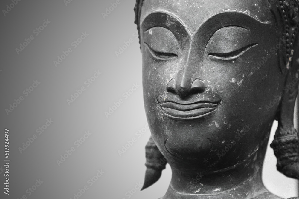 The head of an ancient Buddha statue was made of bronze. image on copy space gray background.