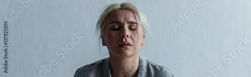 sad blonde woman with climax and closed eyes at home, banner.