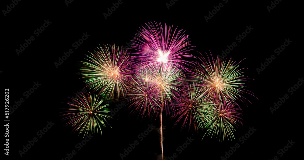 Colorful magical fireworks showing on sea in celebration festival with city lighting and black sky background. 