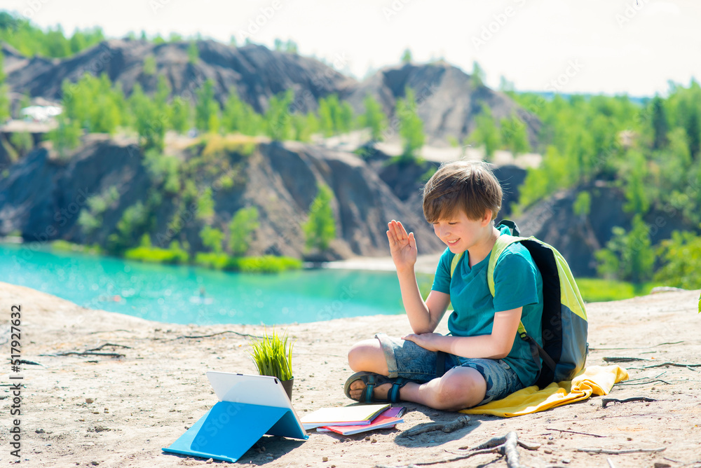 online learning from anywhere in the world. a child in the mountains watches an online lesson, studies at school, takes courses while traveling far from an educational institution