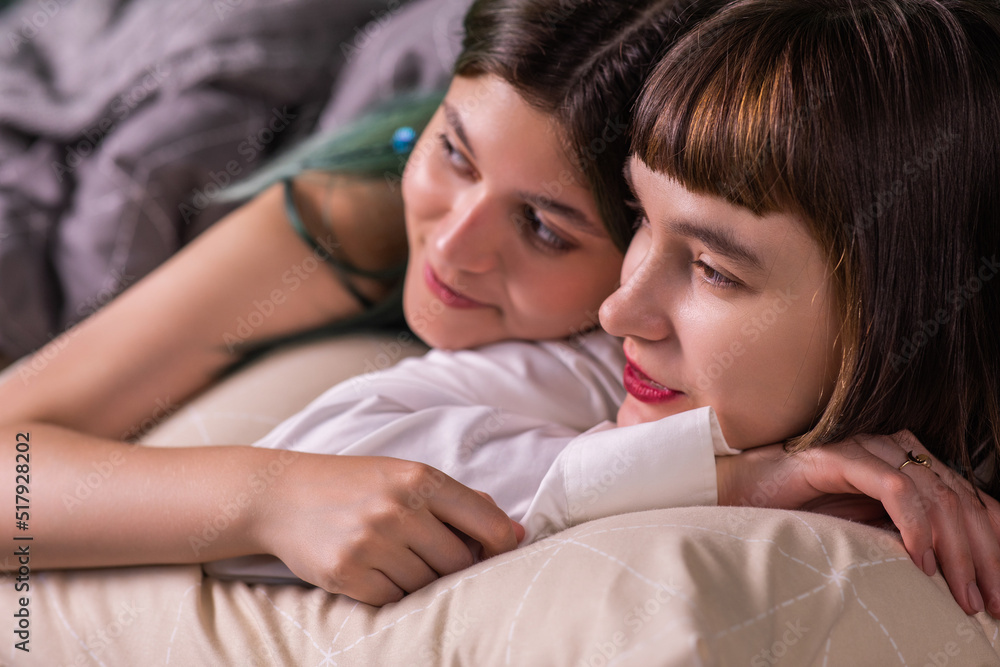 Amazing ladies young looking lesbian couple posing in front of the camera while laying on the bed together hugging each other with love and looking straight Amazing ladies young looking lesbian couple posing in front of the camera while laying on the bed together hugging each other with love and looking straight