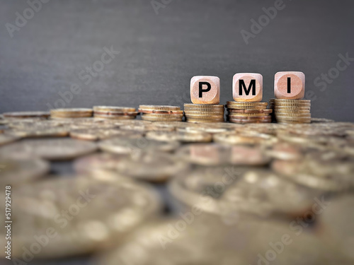 PMI text on wooden cubes with coin stacks background. Business concept. photo