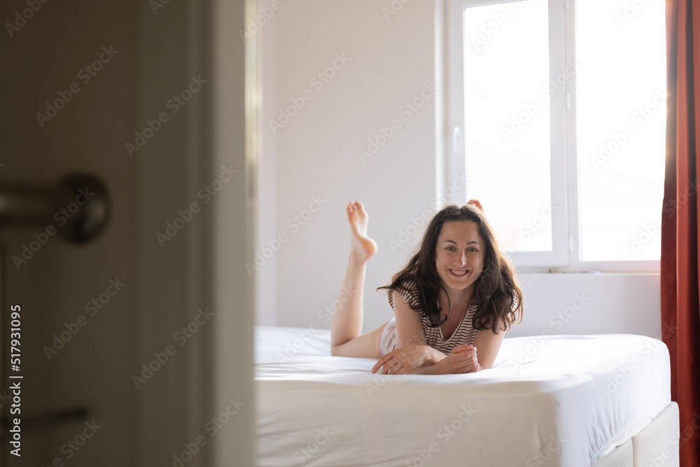 Girl lies on bed, smiling woman in bedroom Girl lies on bed, smiling woman in bedroom