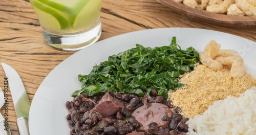 Typical brazilian feijoada with rice, pepper, farofa, kale, caipirinha and cracklings photo