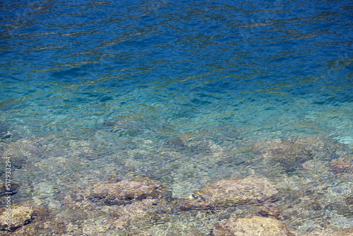 Transparent sea surface with stones on a bottom. Rocky beach  turquoise water for background
