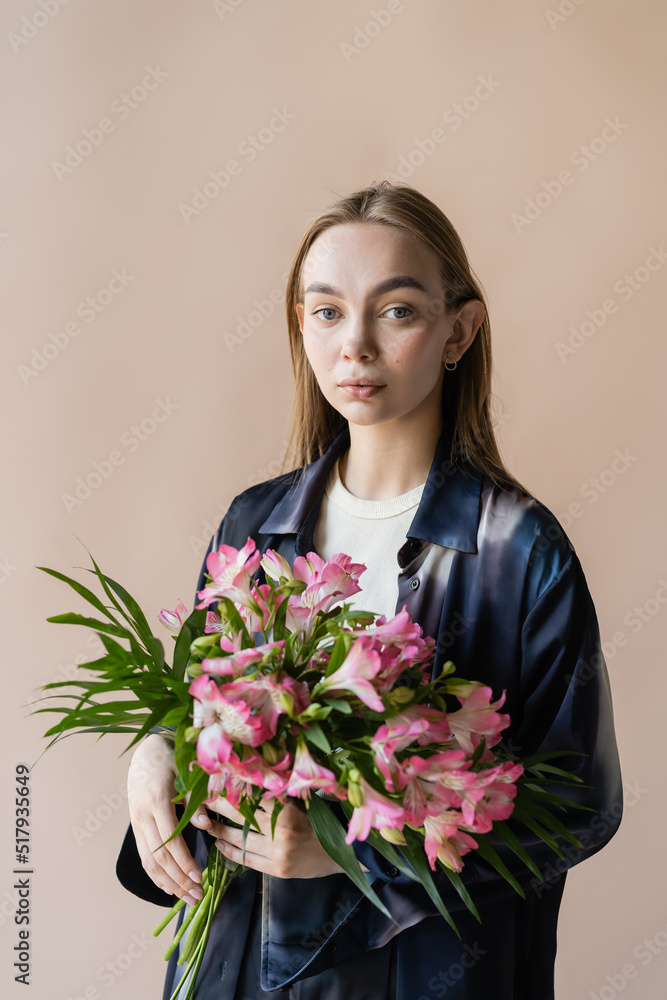 charming woman with alstroemeria flowers looking at camera isolated on beige. charming woman with alstroemeria flowers looking at camera isolated on beige.