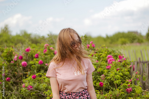beautiful young woman near rose bush
