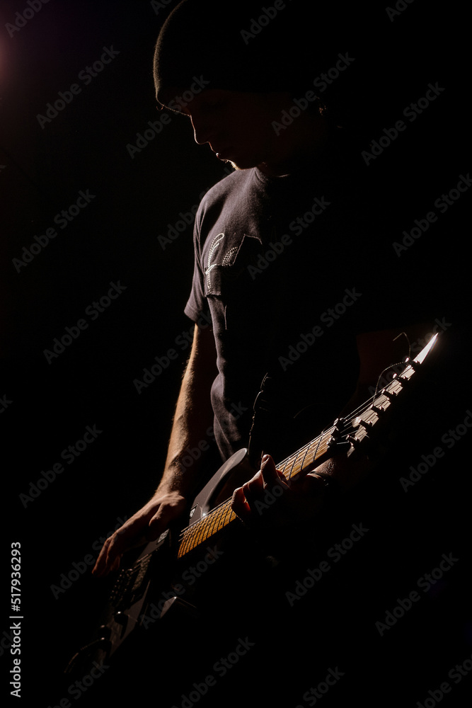 man playing on electric guitar in the dark