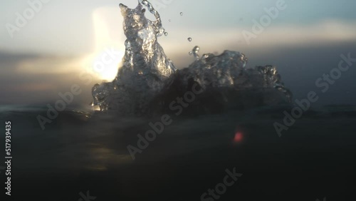 Going under dark gloomy water splashing backlit by sunset glow; drowning pov