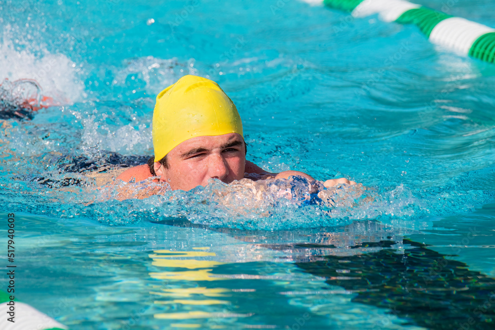Male swimmer uses kickboard amd fins