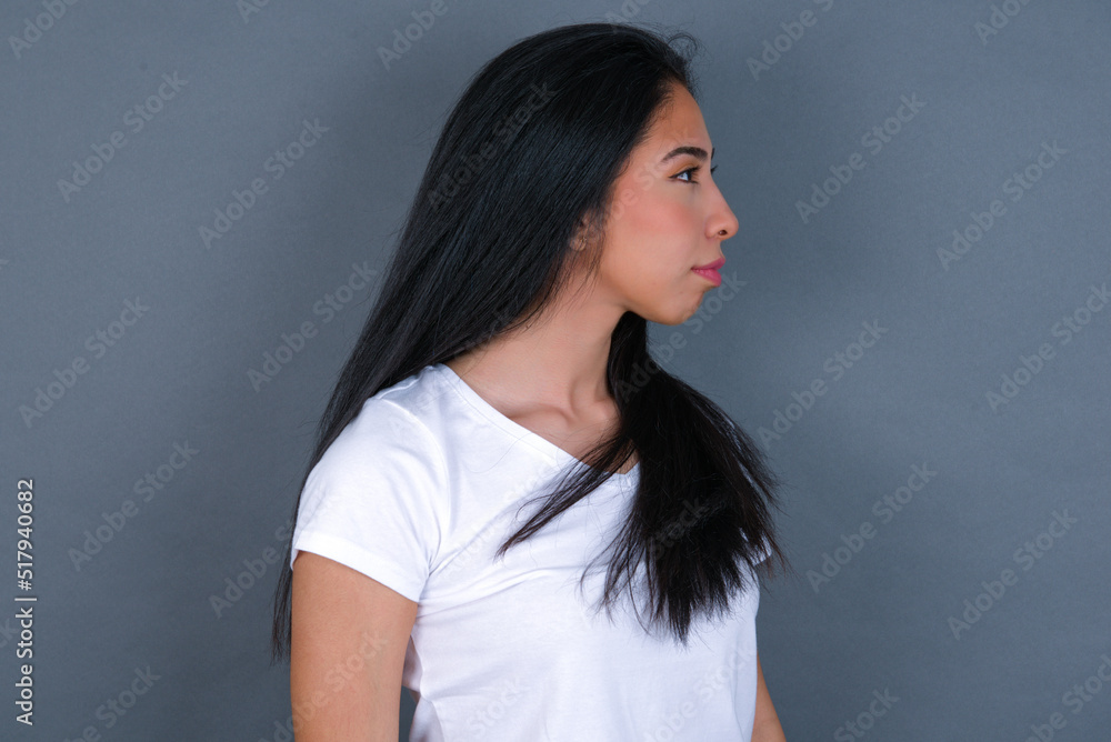 Side view of young happy smiling young beautiful brunette woman wearing white t-shirt over grey background Side view of young happy smiling young beautiful brunette woman wearing white t-shirt over grey background
